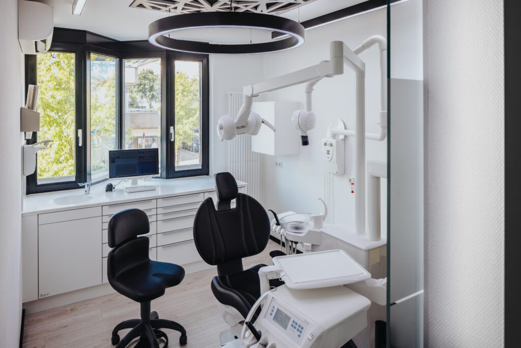Modernes, helles Behandlungszimmer der Zahnarztpraxis Dr. Kollmar in Kassel mit moderner Ausstattung und Glaswänden für eine offene Atmosphäre.