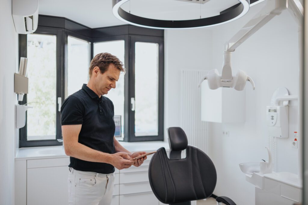 Zahnarzt Dr. Fritz Kollmar bei der digitalen Behandlungsplanung an einem Tablet in seinem modernen Behandlungsraum in Kassel.